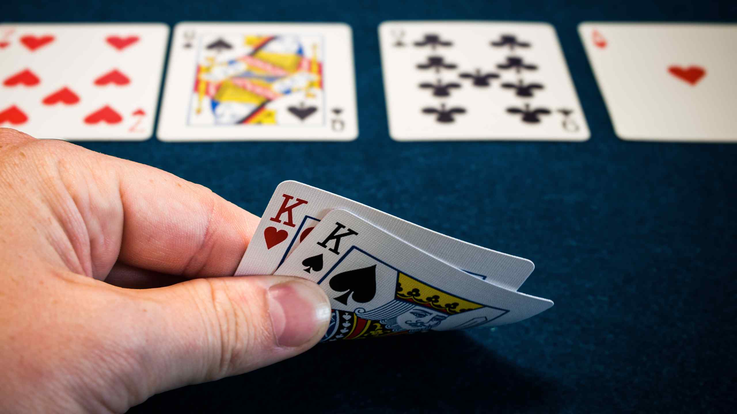 A hand peeling a pair of kings at a poker table.